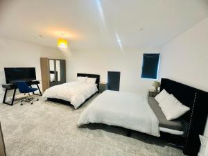 a bedroom with two beds and a desk in it at Hemel Apartments - Hemel Haven in Hemel Hempstead