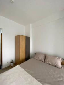 Schlafzimmer mit einem weißen Bett und einem Holzschrank in der Unterkunft Minimalist room at The Nest Apartment by Popobella Near Puri Indah West Jakarta in Jakarta