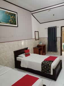 a bedroom with two beds and a table and a window at Vina Vira Hotel in Hagu