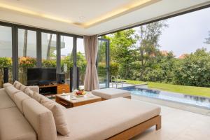 a living room with a couch and a tv and a pool at Daisy Ocean Villa Da Nang in Da Nang