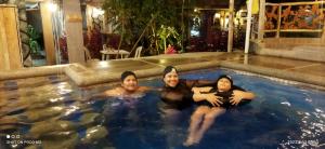three people are sitting in a swimming pool at Ricky's House in Baños
