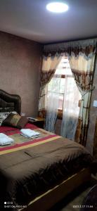 a bedroom with a bed and a window with curtains at Ricky's House in Baños