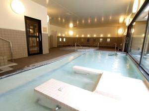 a large swimming pool with blue water in a building at ぽかぽかランド美麻 in Omachi