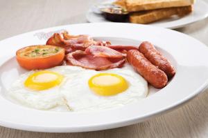 a plate of breakfast food with eggs bacon and toast at Kellys Motel Oakey in Oakey