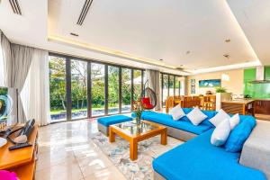 a living room with blue furniture and large windows at Luxury Beach Resort Da Nang in Da Nang