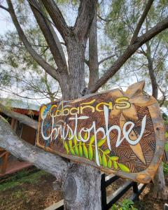 a sign on a tree with graffiti on it at Cabañas Christophe in Hanga Roa