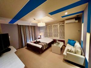 sypialnia z łóżkiem, kanapą i telewizorem w obiekcie ホテル南の風風力3駒ヶ根店 w mieście Komagane