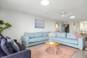 a living room with a blue couch and a table at Luna Blu - Private Apartment Yeppoon in Yeppoon