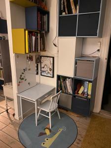 a desk and a chair in a room with a book shelf at Nice flat and area in Copenhagen