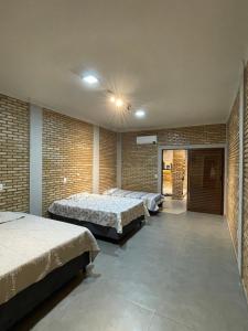 a bedroom with two beds and a brick wall at Chácara ilha do Sol com Piscina aquecida 5km do thermas in Olímpia +29 photos