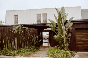 a house with a palm tree in front of a fence at Maison De Plage in Umdloti