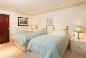 two beds in a bedroom with white walls at Tigh Chailein in Tarbert