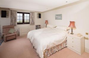 a bedroom with a large white bed and a chair at Tigh Chailein in Tarbert