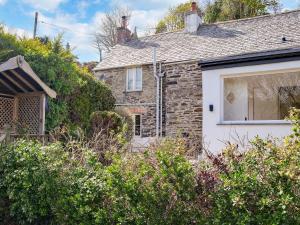 a stone house with a window and bushes at Ivy Cottage - Tq4 in Boscastle