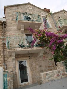 a brick building with a balcony and purple flowers at Apartments Obala Dragovic in Petrovac na Moru