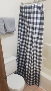 a bathroom with a toilet and a checkered shower curtain at OSU 2 Queen Beds Hotel Room 205 Wi-Fi Hot Tub Booking in Stillwater