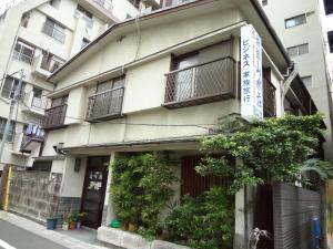 un bâtiment avec des balcons et des plantes dans une rue dans l'établissement Ryokan Sansuiso, à Tokyo