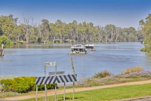 a boat parked on the side of a river near a body of water at Mildura Riverview Motel in Gol Gol