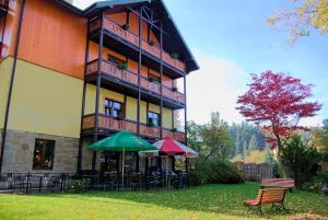 a building with tables and umbrellas in front of it at Pensjonat Lira in Krynica Zdrój