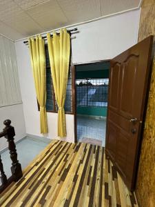 a room with a bed with yellow curtains and a window at Homestay Ummie 