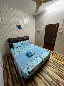a bedroom with a bed with a blue comforter at Homestay Ummie 