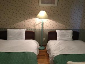 two beds in a room with a lamp on the wall at Kunsthaus in Biei +32 photos
