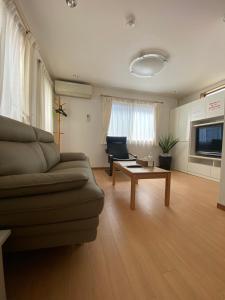 uma sala de estar com um sofá e uma mesa em 田端民泊ー田端ハウス em Tóquio