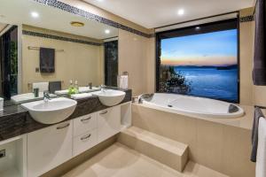 baño con 2 lavabos, bañera y ventana grande en Edge Apartments, en Hamilton Island
