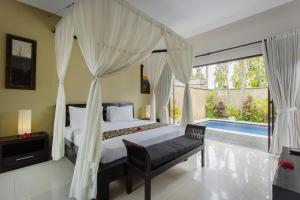 a bedroom with a canopy bed and a swimming pool at The Bidadari Villas and Spa Umalas - CHSE Certified in Canggu