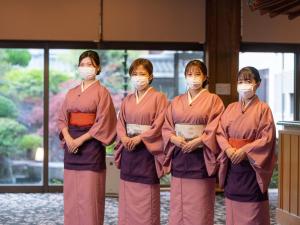 Un gruppo di quattro donne che indossano maschere in un edificio di Meitei no Yado Hotel Koshien a Fuefuki