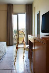um quarto de hotel com uma cadeira e uma secretária com uma televisão em Golden Beach em Hersonissos