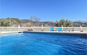 a swimming pool with blue chairs and a white fence at Villa Pastor, Torrox, Málaga in Torrox