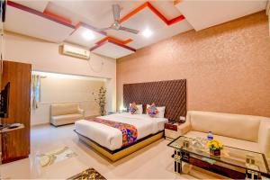 a bedroom with a bed and a couch and a table at FabHotel Prime Rockstar Suites in Kolkata