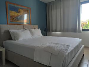 1 dormitorio con 1 cama blanca grande y ventana en Dora's House comfortable apartment with a yard and view, en Pyrgadikia