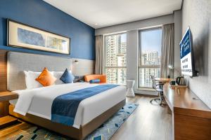 Holiday Inn Express Chongqing Guanyinqiao , an IHG Hotel في تشونغتشينغ: غرفة الفندق بسرير كبير ومكتب