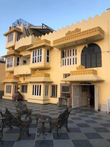 a large yellow building with benches in front of it at Jai Villa Homestay in Udaipur