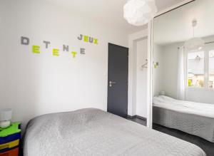 ein weißes Schlafzimmer mit einem Bett und einem Spiegel in der Unterkunft L escale bretonne- séjour chez l habitant in Mordelles