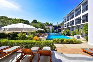 a hotel with a pool and chairs and an umbrella at Aonang Viva Resort - SHA Plus in Ao Nang Beach