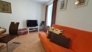 a living room with an orange couch and a television at Holiday House Erna in Izola