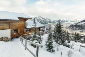 a log cabin in the snow with mountains in the background at Chalet le Grand Ours in La Tzoumaz