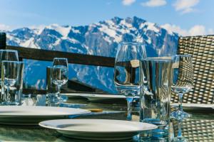 une table avec des verres et des assiettes sur une table avec des montagnes dans l'établissement Chalet le Grand Ours, à La Tzoumaz