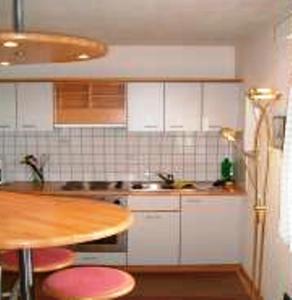 a kitchen with white cabinets and a table with pink stools at Pension Angergut in Cermes