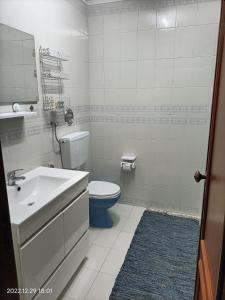 a white bathroom with a toilet and a sink at Apartamento Praia da Torreira in Torreira