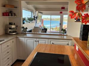 a kitchen with white cabinets and a view of the ocean at Eden by the Beach in Kiama