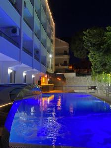 ein Schwimmbad mit einem Brunnen vor einem Gebäude in der Nacht in der Unterkunft Marla Didim Otel in Didim