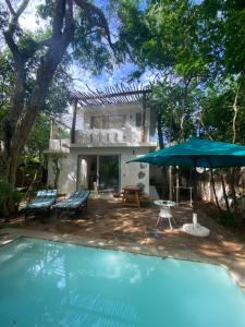 a house with a swimming pool and an umbrella at The Shore House Diani - 2 Bedroom Villa with a pool in Galu