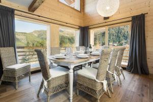 a dining room with a table and chairs and windows at Chalet Grand Roi in La Tzoumaz