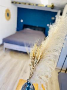 a feather in a vase on a table with a bed at Jolie chambre indépendante in Limoges