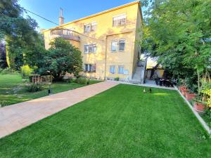 a large yellow building with a lawn in front of it at Blue Bird Citadel Apartment in Budapest