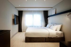 Un dormitorio con una gran cama blanca y una ventana en The Connoisseur Residence Hotel en Seúl